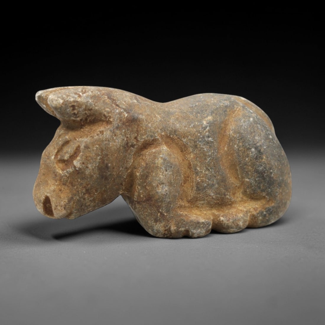 Ancient Stone Bovid Amulet - Near Eastern Animal Figurine, 27ZR: This artifact is a carved stone bovid amulet, executed in the stylized zoomorphic tradition of the ancient Near East. The amulet depicts a recumbent bovid (likely a bull or ox) with simplified anatomi