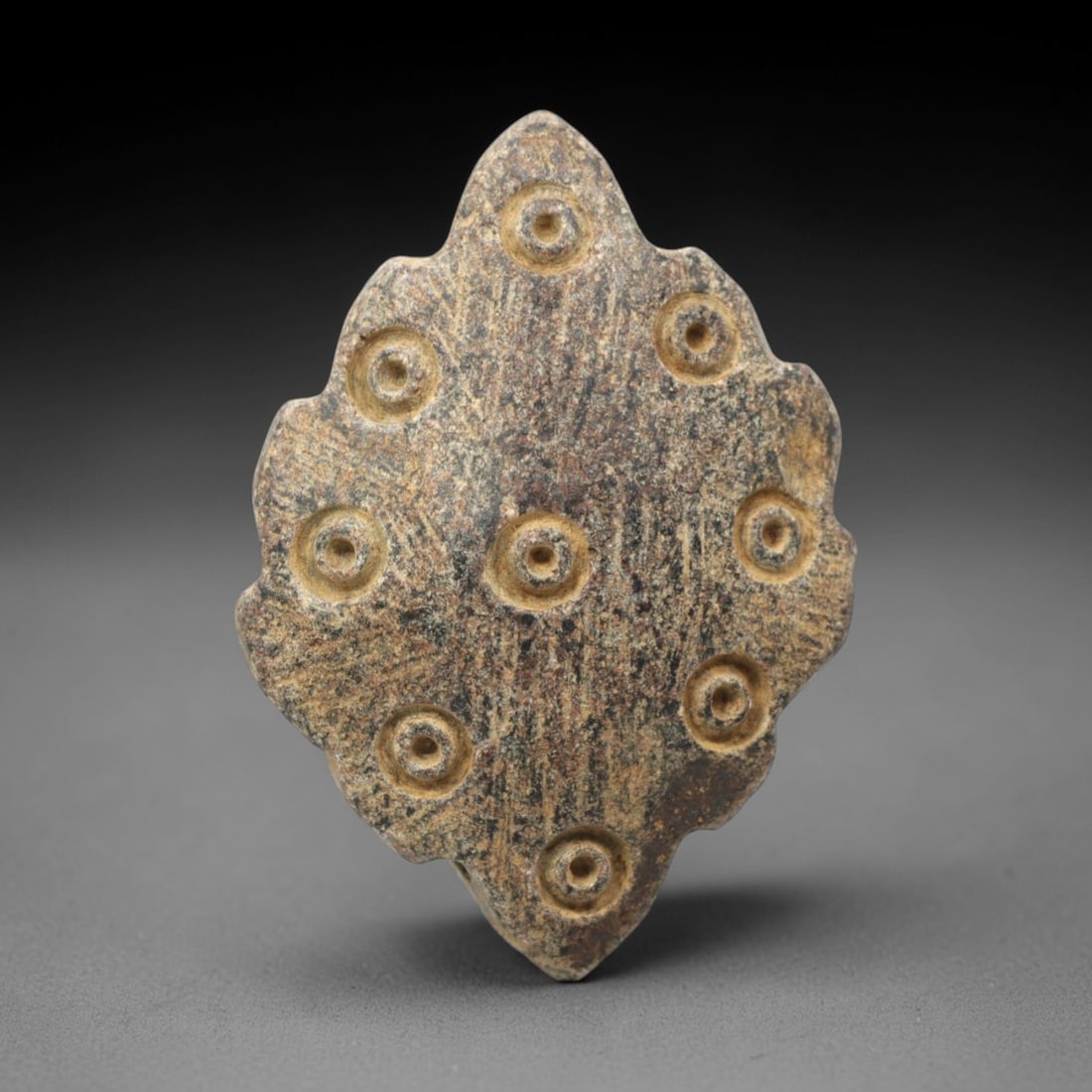 Ancient Steatite Amulet - Near Eastern Concentric Circles, 27XV: Carved from dense steatite, this ancient amulet displays a symmetrical arrangement of concentric circle motifs, executed with deliberate, controlled carving characteristic of Near Eastern metalworking