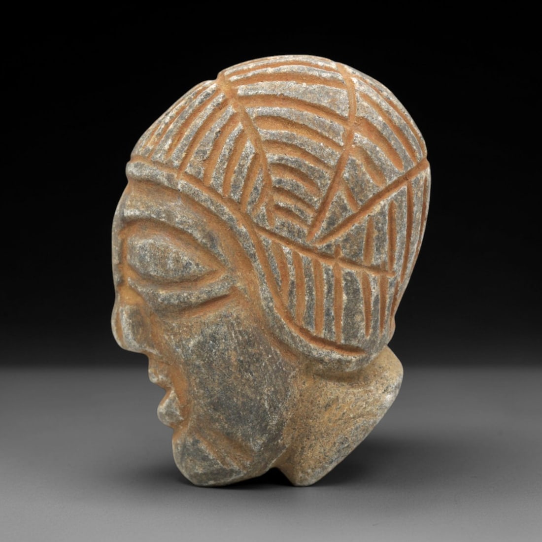 Ancient Stone Head Amulet - Near Eastern Figurine, 87ZP: This artifact is a carved stone head amulet, executed in the stylized anthropomorphic tradition of the ancient Near East. The amulet features a profile view with distinct facial elements: deeply incis