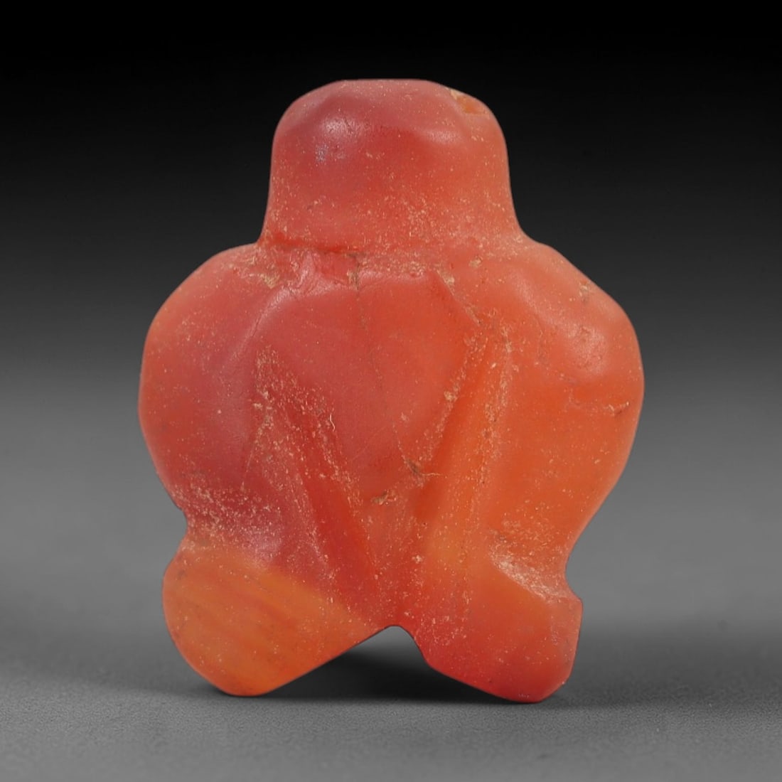 Ancient Carnelian Bird Amulet - Near Eastern Figurine, 65AJ: Carved from vibrant red carnelian, this amulet is formed as a stylized bird with a rounded head and broad, outstretched wing-like projections, consistent with ancient Near Eastern protective amulet tr