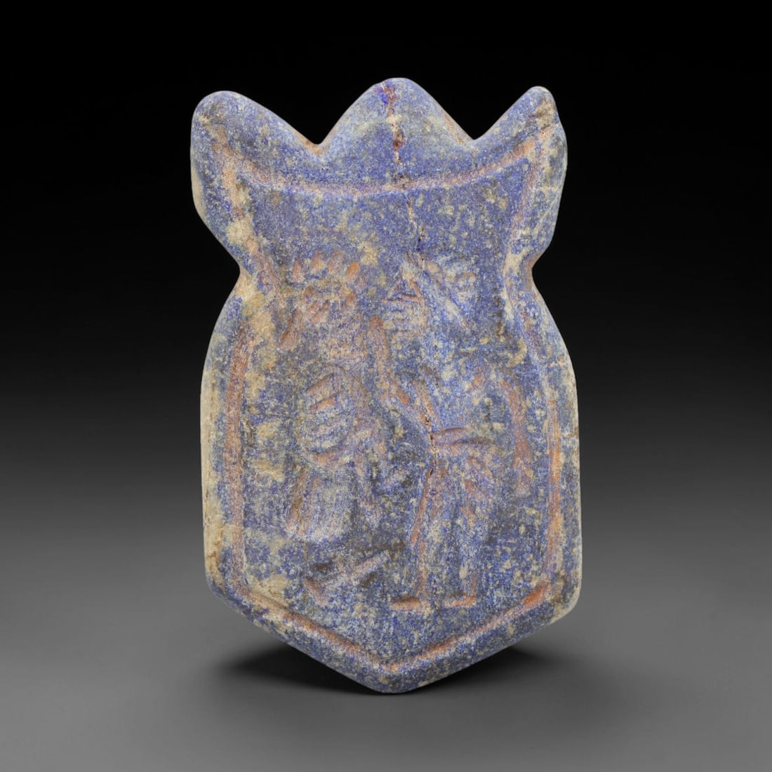 Ancient Lapis Lazuli Amulet - Near Eastern Human Bird Idol, 31ZX: Carved from lapis lazuli, the amulet takes the form of a shield-shaped plaque with a raised, trilobed suspension lug at the apex, a hallmark of ancient Near Eastern amuletic craftsmanship. The front s