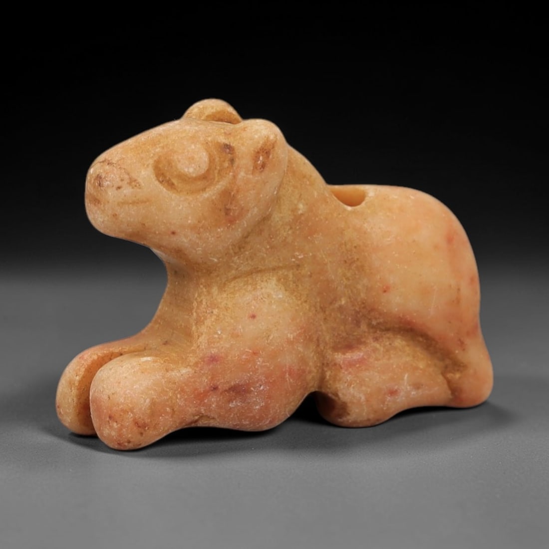 Ancient Pinkish-White Stone Recumbent Feline - Near Eastern Amulet, 81AD: Carved from finely grained pinkish-white stone with subtle amber mineral veining, this amulet depicts a recumbent feline in a compact, elegantly rounded form. The creature is rendered in a prone resti