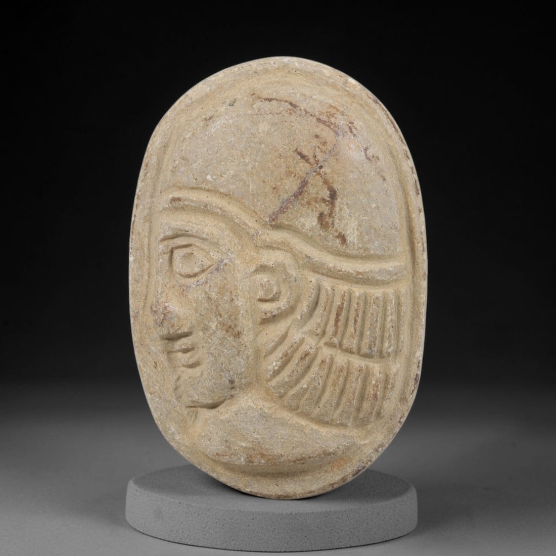 Ancient Stone Amulet - Near Eastern Bust Plaque Pendant, 79FY: Carved from light-colored stone, the amulet is an oval plaque crafted in the ancient Near Eastern style, featuring a raised relief portrait of a human bust in profile. The surface bears incised detail