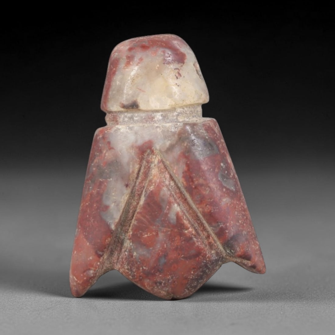Ancient Stone Amulet - Egyptian Ritual Pendant, 73AP: This artifact is carved from variegated red and white stone with a weathered, earthy patina and natural mineral veining, exhibiting stylized geometric detailing consistent with ancient Egyptian stonew