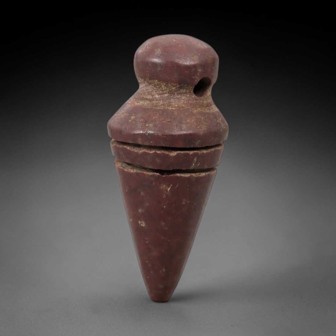 Ancient Stone Conical Amulet - Near Eastern Ritual Figurine, 62AG: This amulet is carved from a single piece of deep reddish-brown stone, exhibiting a granular texture with subtle ochre patina and faint mineral flecks across its surface. The form is a stylized conica