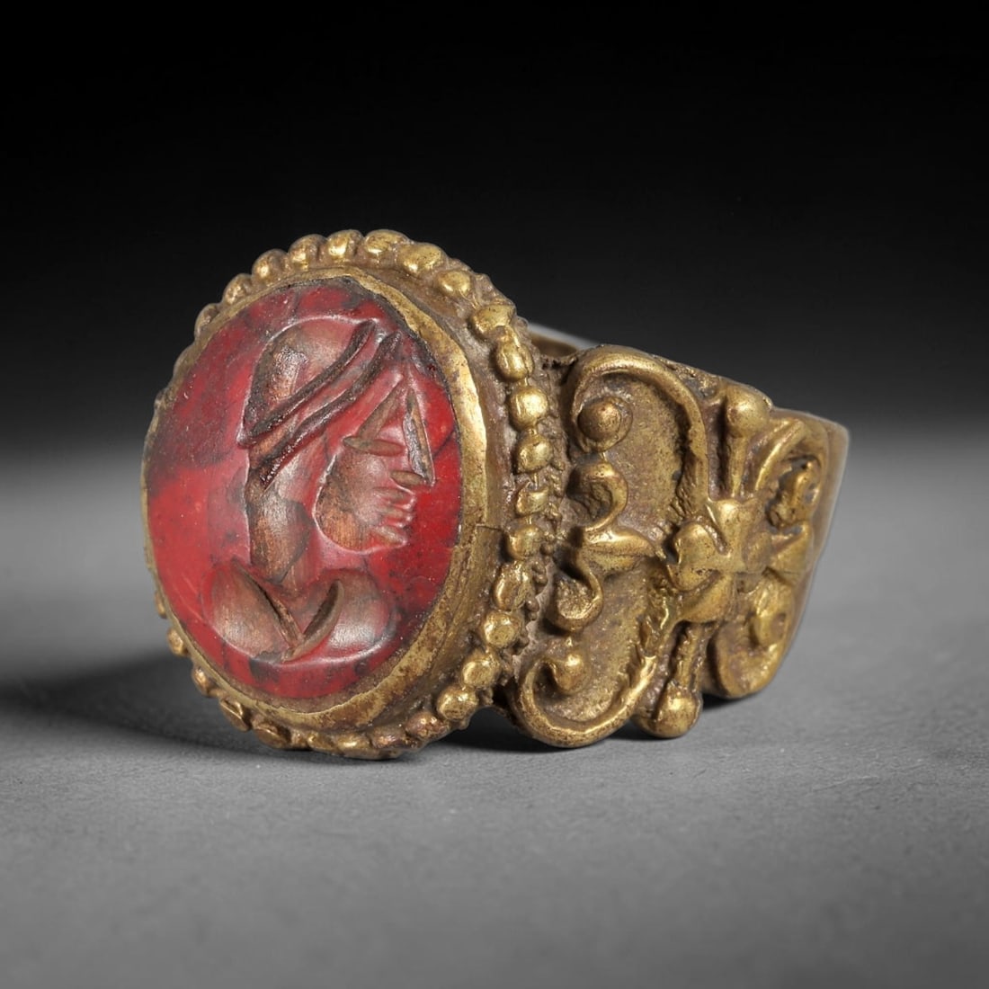 Antique Qajar Dynasty Red Jasper Portrait Intaglio Ring - Size 9 US, 83FY: Crafted from gilt brass with an ornate circular bezel, this ring features a carved red jasper intaglio stone at its center, depicting an incised profile portrait motif characteristic of Qajar-era Pers