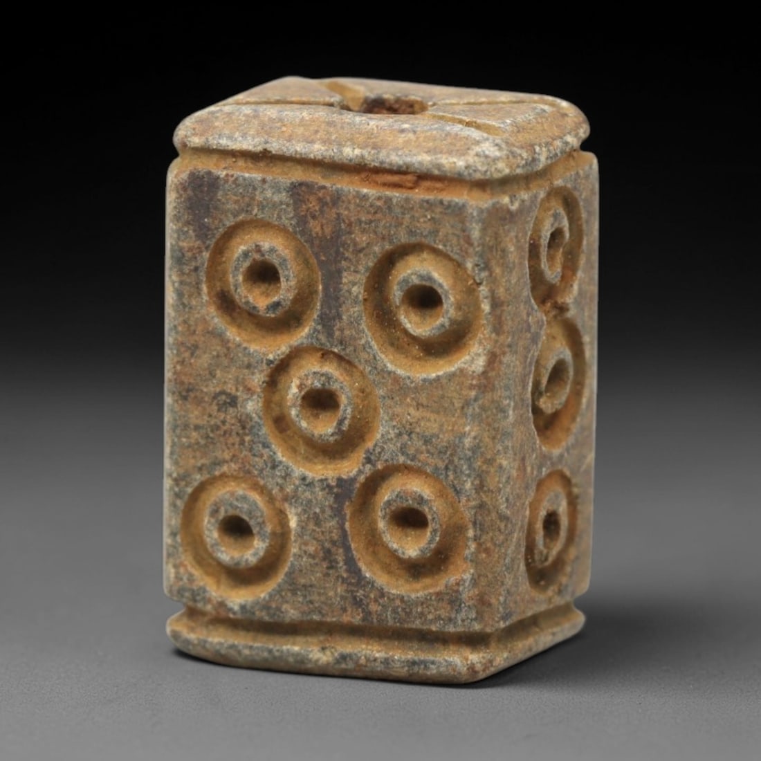 Ancient Steatite Amulet Bead - Near Eastern Concentric Circles, 15XV: Carved from dense steatite, this ancient amulet bead features a rectangular prism form with a vertical suspension hole at the top, designed for wearable use. Its visible faces are decorated with raise
