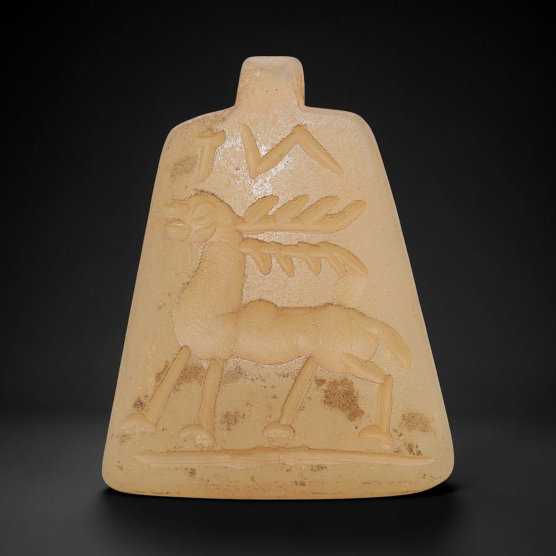 Ancient Chalcedony Stag Amulet - Near Eastern Carving, 47ZX: This artifact is carved from pale, translucent chalcedony, exhibiting a soft, aged patina and subtle surface weathering consistent with ancient Near Eastern antiquities. The amulet takes a trapezoidal