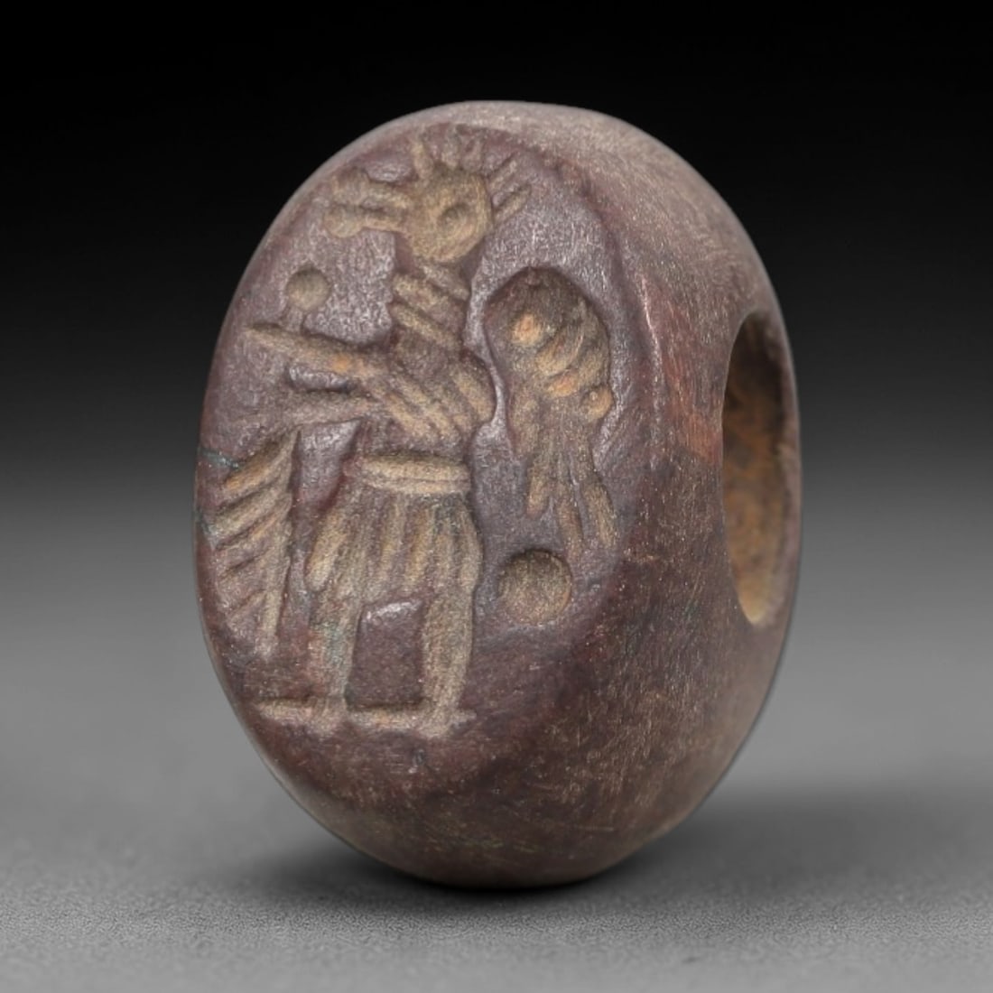 Ancient Red Stone Stamp Seal - Near Eastern Anthropomorphic Figure, 37AN: Carved from dense, reddish-brown stone, this hemispherical stamp seal features an incised motif of a standing anthropomorphic figure in profile, adorned with a stylized headdress and segmented garment