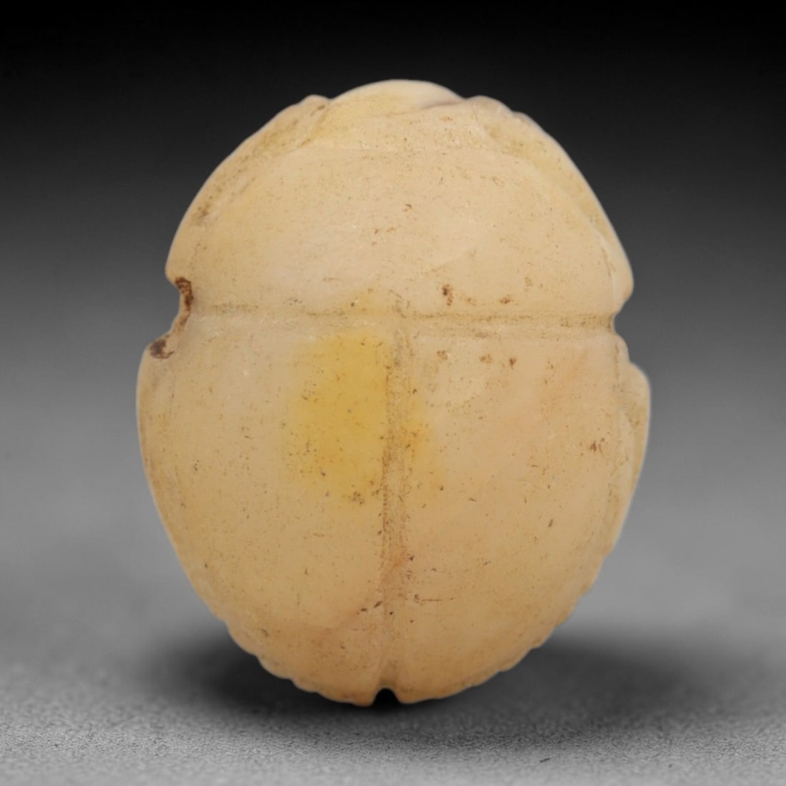 Ancient Travertine Scarab - Egyptian Amulet Figurine, 49ZW: This amulet is carved from pale creamy travertine, shaped into the classic scarab beetle form, a symbol of rebirth and protection in ancient Egyptian cosmology. Incised lines delineate the dorsal elyt
