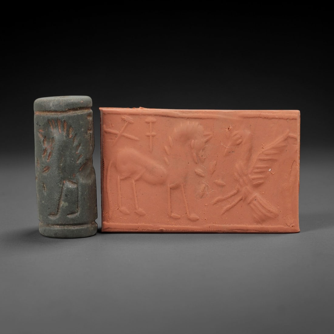 Ancient Near Eastern Stone Cylinder Seal - Horse & Bird Motif, 71AH: Carved from fine-grained stone, this cylinder seal features incised depictions of equine and avian figures, a motif characteristic of ancient Near Eastern glyptic art. The piece exhibits a natural red
