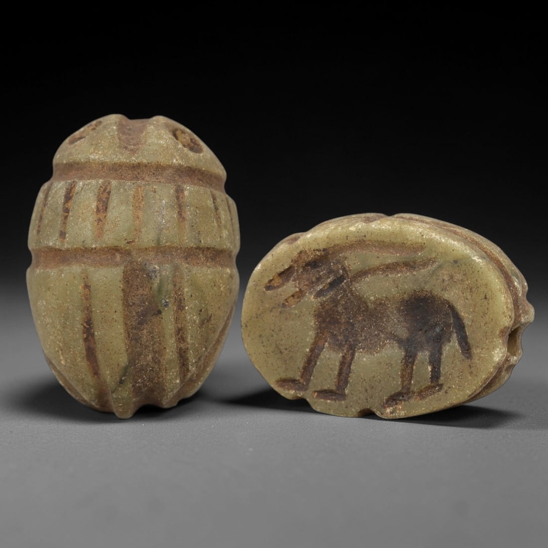Ancient Steatite Scarab Stamp Seal - Near Eastern Donkey Figure, 84AM: Carved from muted green steatite, this Near Eastern scarab stamp seal features a dorsal scarab pattern with incised linear details defining the elytra and decorative segments, while the ventral face d