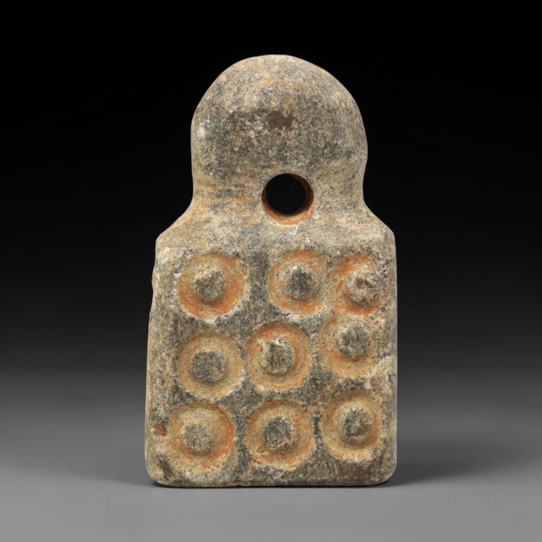 Ancient Steatite Amulet - Near Eastern Concentric Circles, 22XV: Carved from dense steatite, this ancient amulet features a distinctive form with a rounded upper section and a rectangular lower panel, with a large central suspension hole for wearable use. The recta