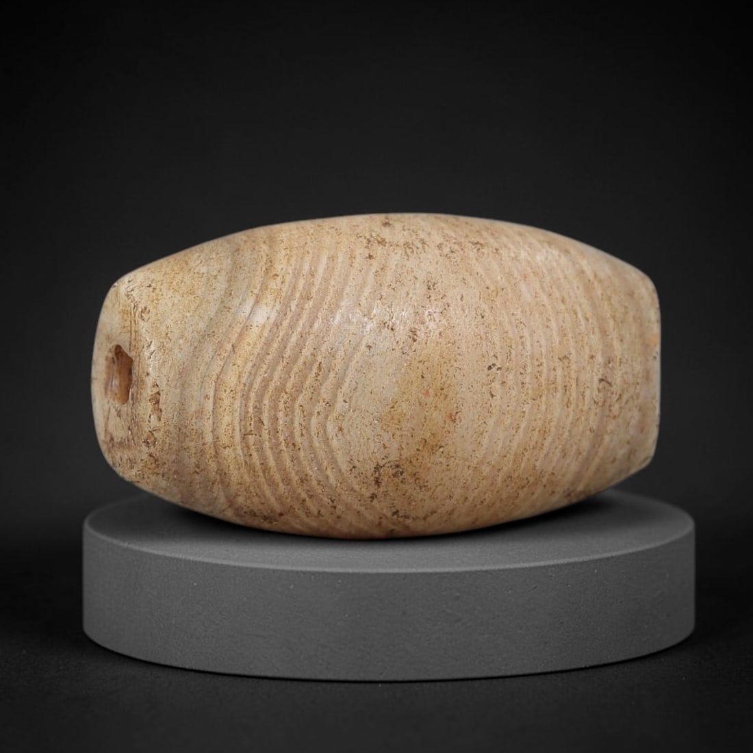 Ancient Agate Bead - Silk Road Bicone Amulet: Carved from banded agate, the bead features a smooth symmetrical bicone (double-pointed) form with a polished surface that highlights the stone's fine wavy concentric banding in warm cream and soft ta