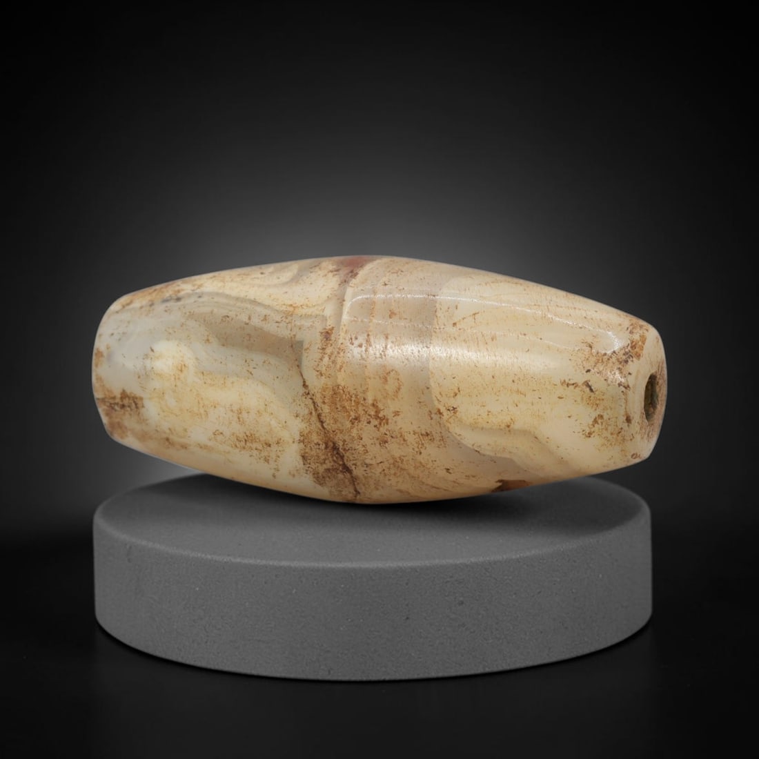 Ancient Agate Bead - Indus Valley Banded Carving: This artifact is crafted from banded agate, showcasing soft, swirling banding in creamy ivory and warm honey-amber hues, with subtle earthy mineral staining and delicate surface weathering across its