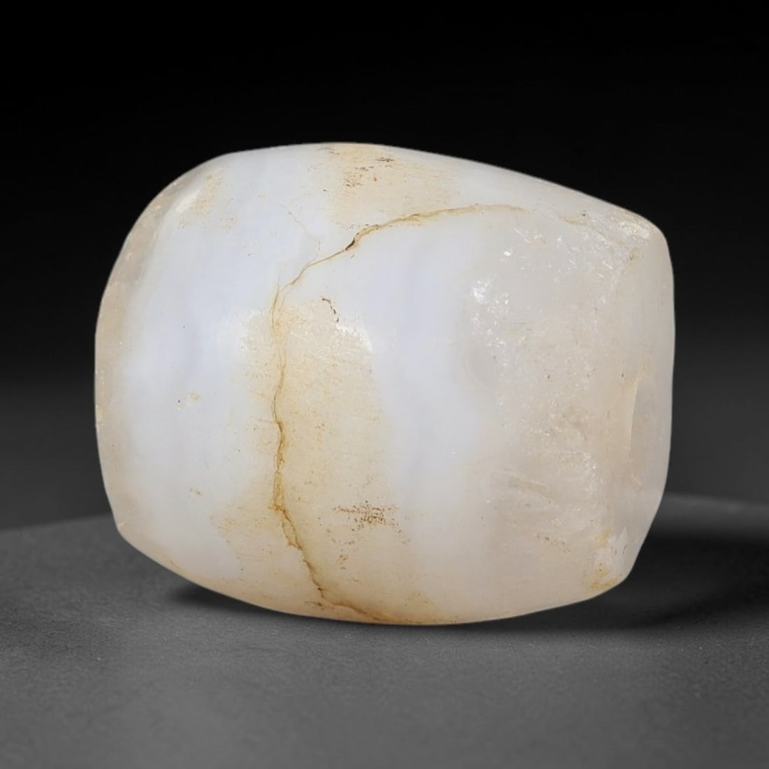 Ancient Agate Bead - Indus Valley Amulet, 31BD: This artifact is crafted from pale milky white agate, exhibiting subtle wavy banding across its smooth barrel form, shaped through skilled ancient lapidary work. The bead features a precisely drilled