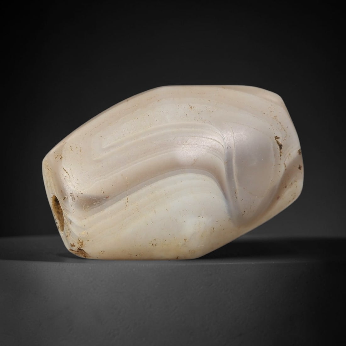Ancient Agate Bead - Silk Road Amulet: Carved from banded agate, the bead features a smooth, polished surface that highlights the stone's natural wavy concentric banding, ranging from creamy white to soft taupe and pale peach hues. A longi