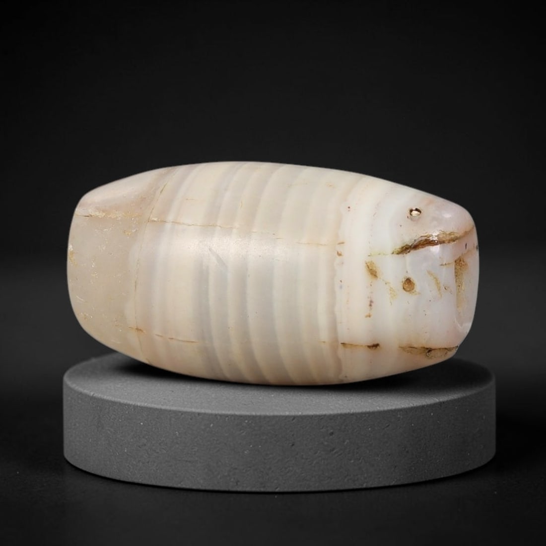Ancient Agate Bead - Silk Road Bicone Amulet: Carved from banded agate, the bead features a smooth symmetrical bicone (double-pointed) form with a polished surface that highlights the stone's fine parallel concentric banding in creamy white and s