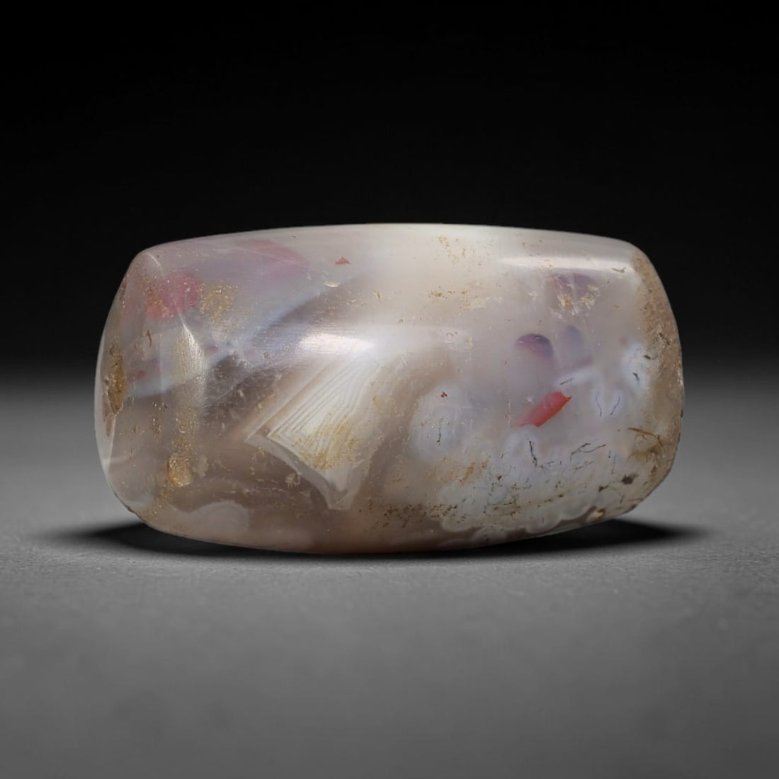 Ancient Agate Bead - Silk Road Cylinder Amulet: Carved from banded agate, the bead features a cylindrical barrel form with a smooth, polished surface that highlights the stone's natural inclusions, including striking red and purple mineral flecks,