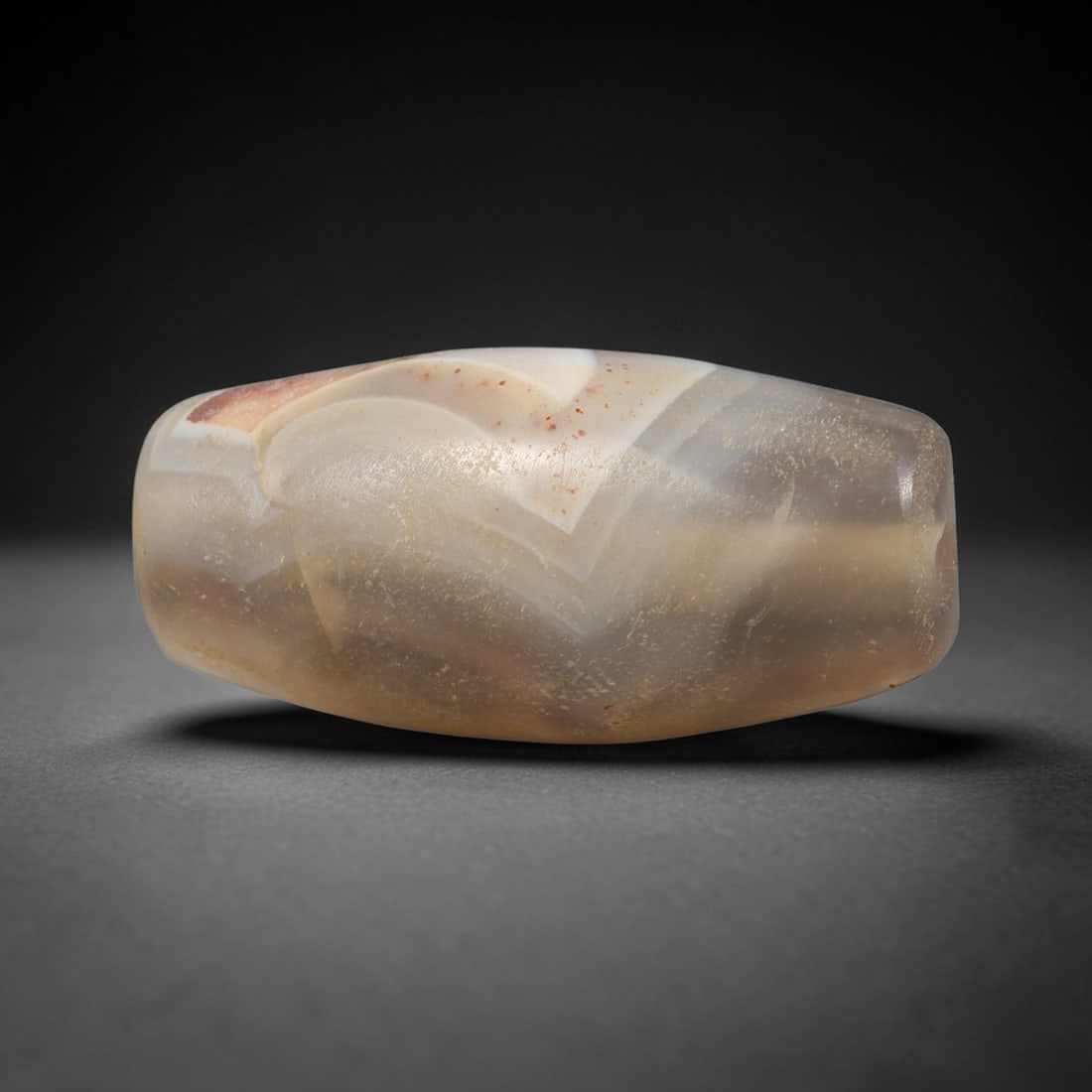 Ancient Agate Bead - Silk Road Indus Valley Barrel Bead: Carved from banded agate, the bead is fashioned in a classic barrel form, with a central drilled perforation for suspension. The stone exhibits striking natural banding in creamy white, pale grey, and