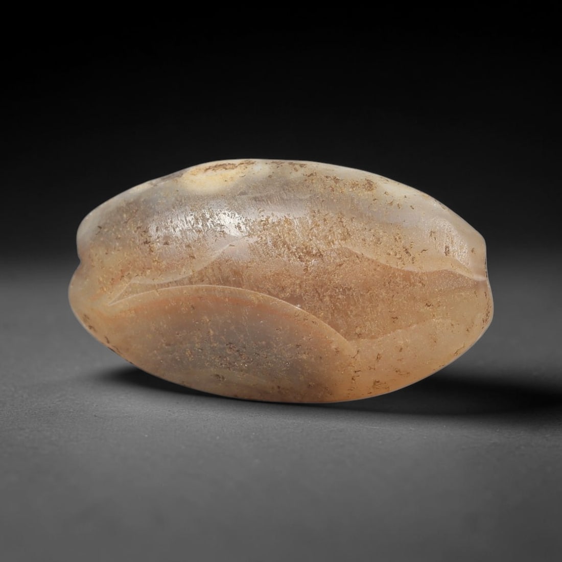 Ancient Agate Bead - Silk Road Melon Amulet: Carved from banded agate, the bead features a carved melon form with a smooth, polished surface that highlights the stone's natural concentric banding, ranging from translucent milky white to warm hon