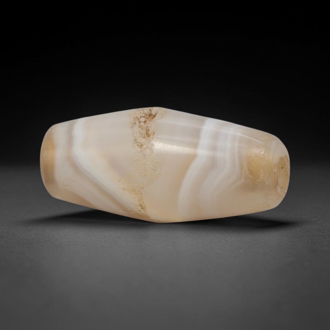 Ancient Agate Bead - Silk Road Bactrian Amulet: This bead is carved from delicately banded translucent agate, exhibiting refined lapidary craftsmanship consistent with ancient Bactrian and Silk Road bead-making traditions. The elongated bicone form
