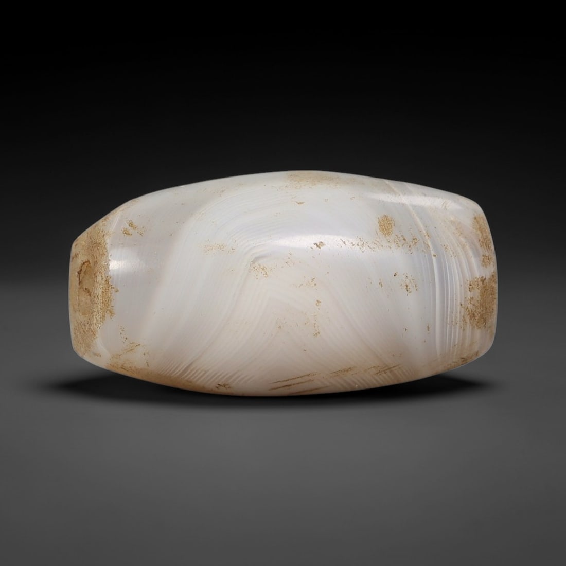 Ancient Banded Agate Bead - Silk Road Indus Valley Barrel Bead, 26BC: Carved from banded agate, the bead is fashioned in a compact barrel form, with a central drilled perforation for suspension. The stone exhibits striking, fine concentric banding in milky white and sof