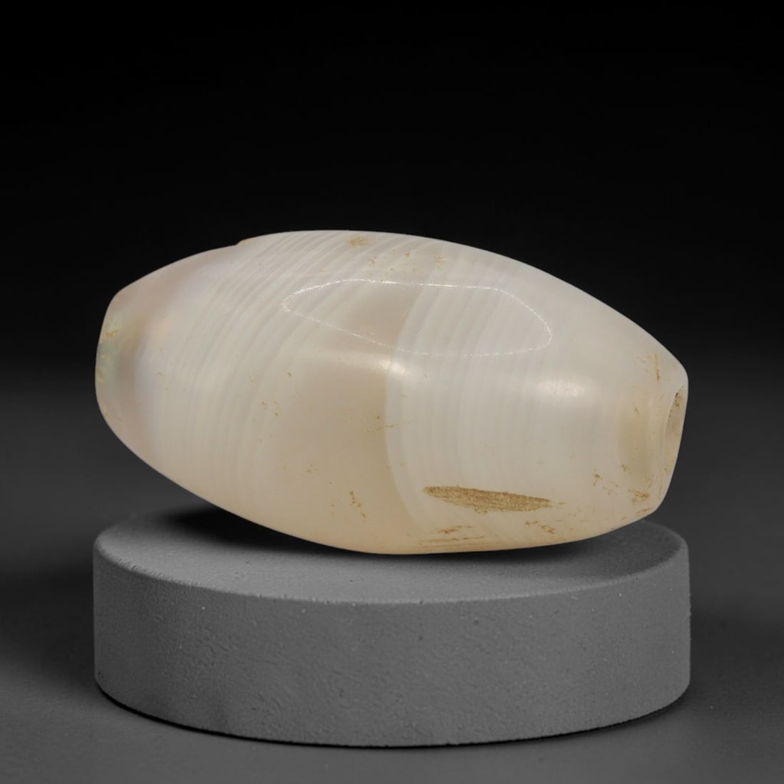 Ancient Banded Agate Bead - Western Asiatic Miniature Amulet: This bead is expertly carved from naturally banded translucent agate, showcasing fine lapidary craftsmanship consistent with the ancient bead-making traditions of the Indus Valley and Bactrian regions