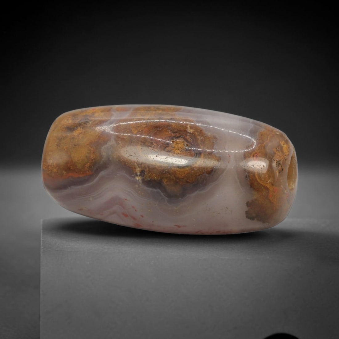 Ancient Banded Agate Bead - Western Asiatic Miniature Amulet: This bead is masterfully carved from naturally banded translucent agate, showcasing exceptional lapidary craftsmanship consistent with ancient bead-making traditions of the Indus Valley and Bactrian r