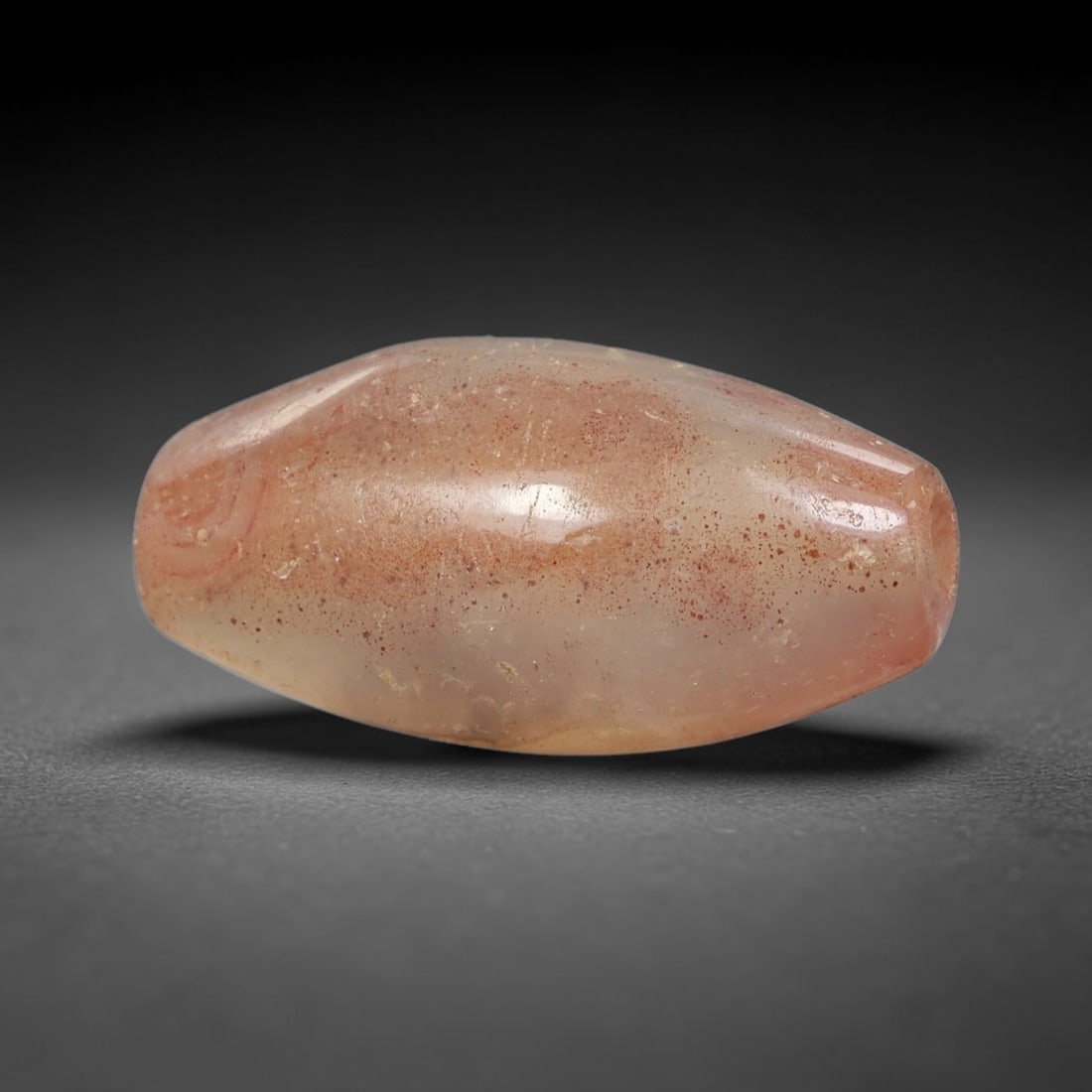 Ancient Agate Bead - Silk Road Bicone Amulet: Carved from translucent banded agate, the bead exhibits a symmetrical bicone form with a smooth, polished surface that showcases the stone's pale milky base and warm reddish-brown mineral inclusions.