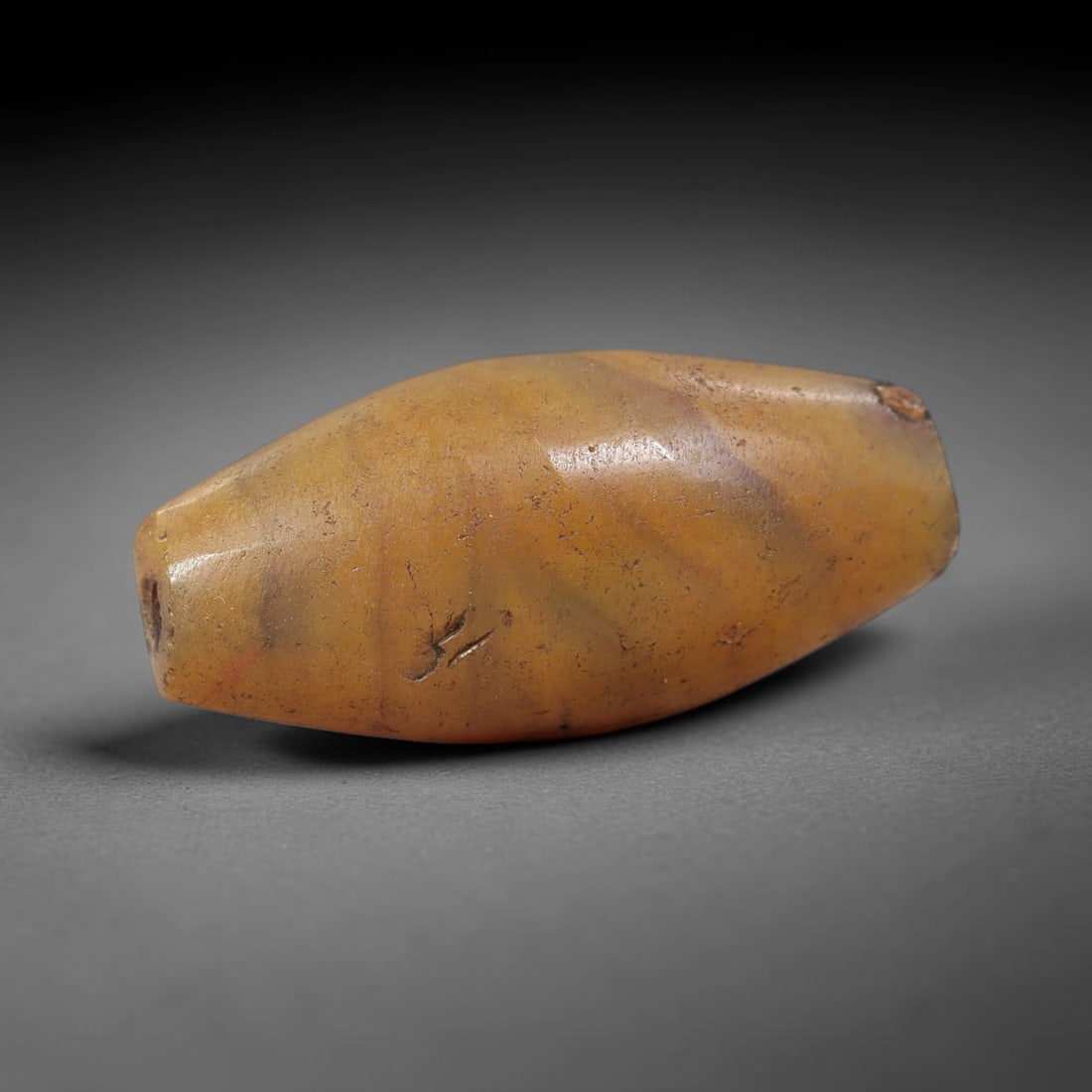 Ancient Jasper Bead - Silk Road Bicone Amulet: Carved from natural jasper, the bead features a smooth symmetrical bicone (double-pointed) form with a polished surface that highlights the stone's rich warm honey-amber base and subtle internal bandi