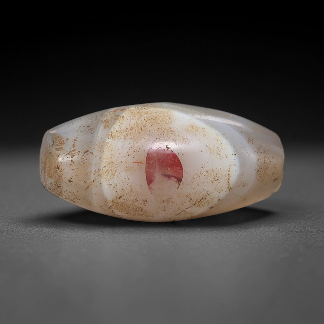 Ancient Banded Agate Bead - Silk Road Indus Valley Barrel Bead: Carved from banded agate, the bead is fashioned into a compact barrel shape, centered with a drilled perforation for suspension. The stone features natural banding in milky white, soft beige, and subt