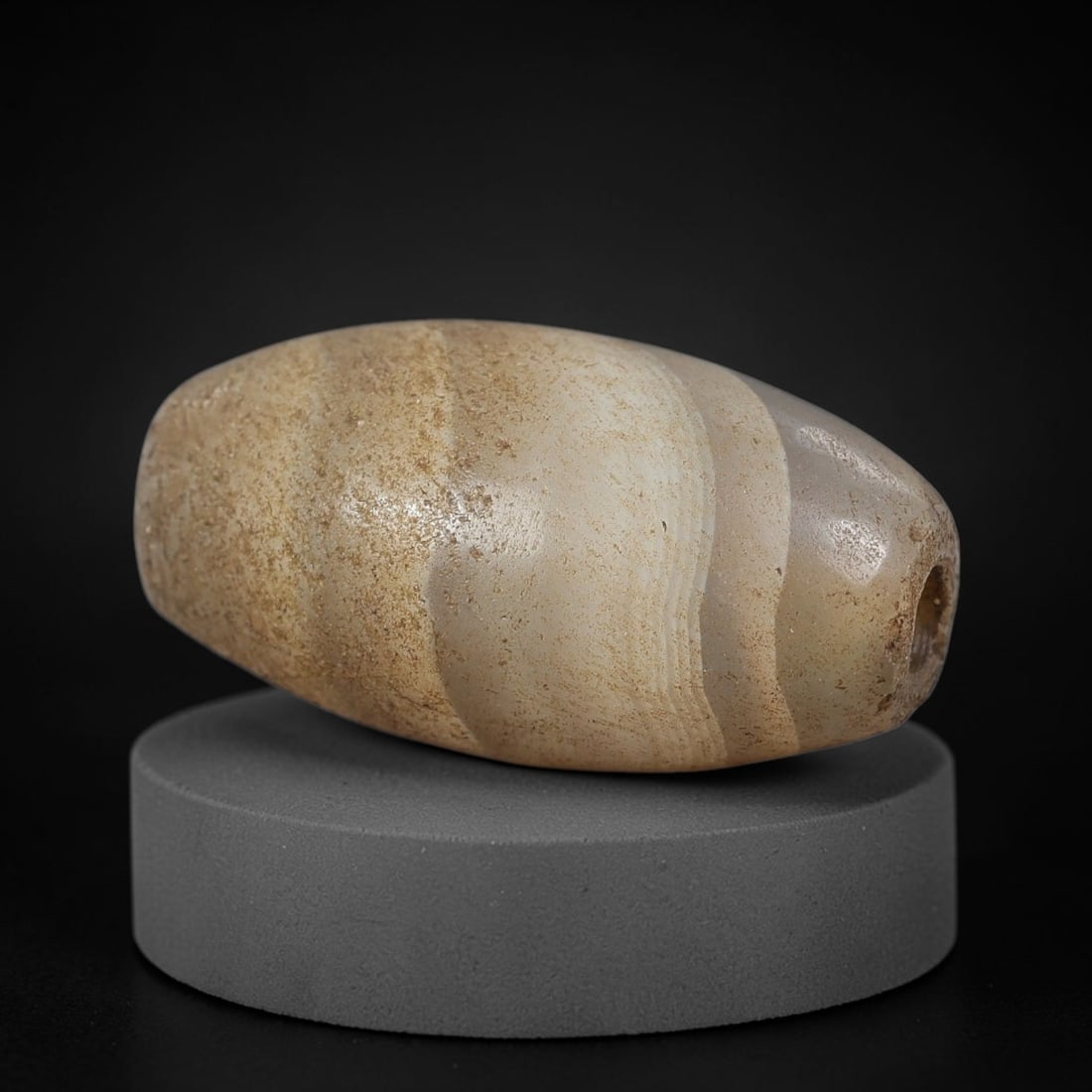 Ancient Agate Bead - Silk Road Bicone Amulet: Carved from banded agate, the bead features a smooth symmetrical bicone (double-pointed) form with a polished surface that highlights the stone's soft concentric banding in creamy white, warm taupe, a