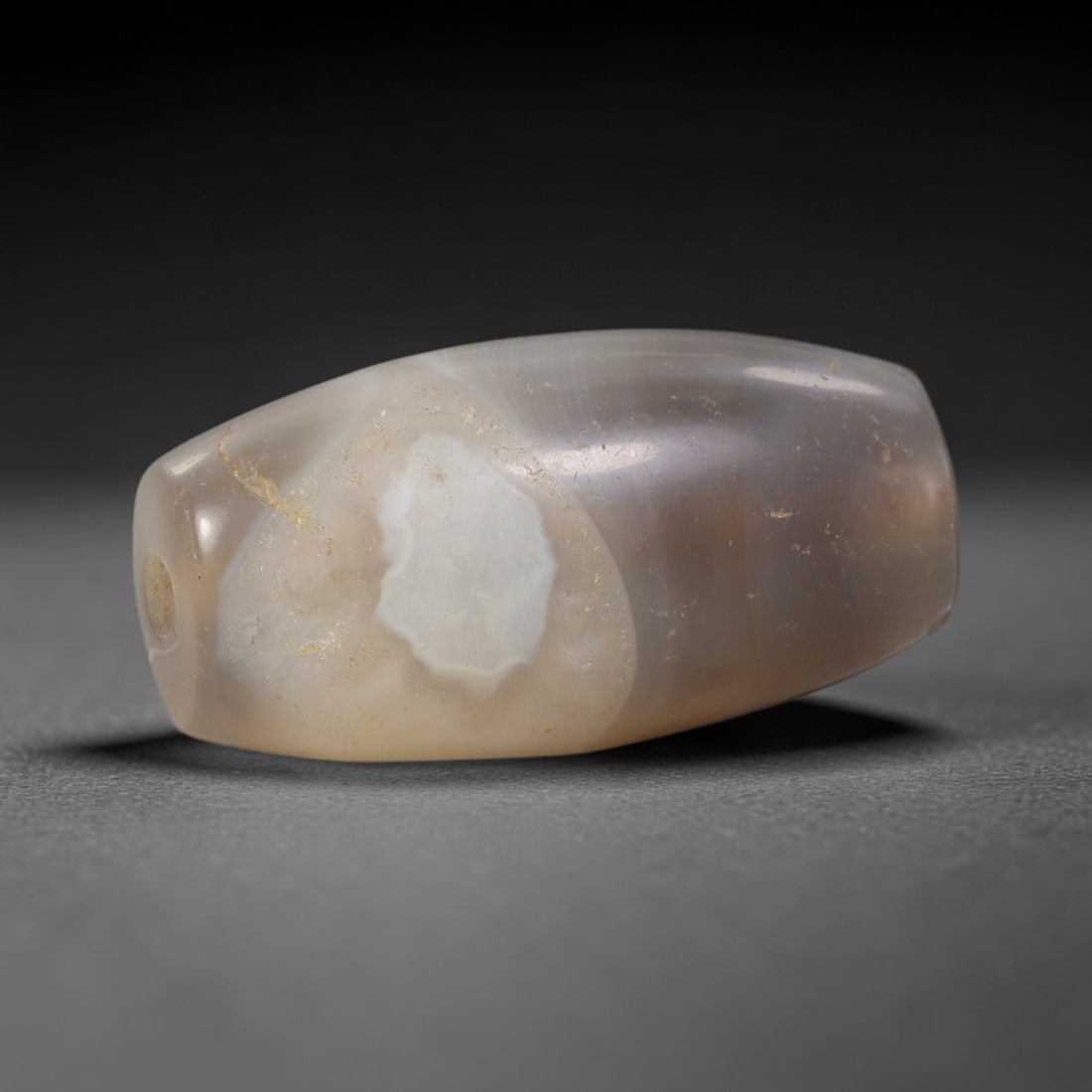 Ancient Banded Agate Bead - Silk Road Indus Valley Barrel Bead: Carved from banded agate, the bead is fashioned in a compact barrel form, with a central drilled perforation for suspension. The stone exhibits a striking natural banding pattern, with a distinct shie