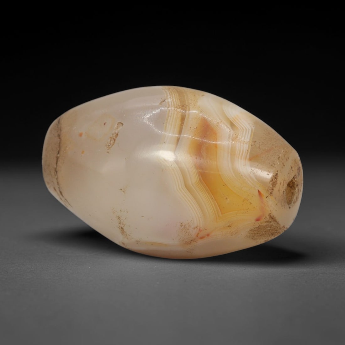 Ancient Banded Agate Bead - Western Asiatic Amulet: This bead is masterfully carved from richly banded translucent agate, showcasing exceptional lapidary craftsmanship consistent with ancient bead-making traditions of the Indus Valley and Bactrian regi
