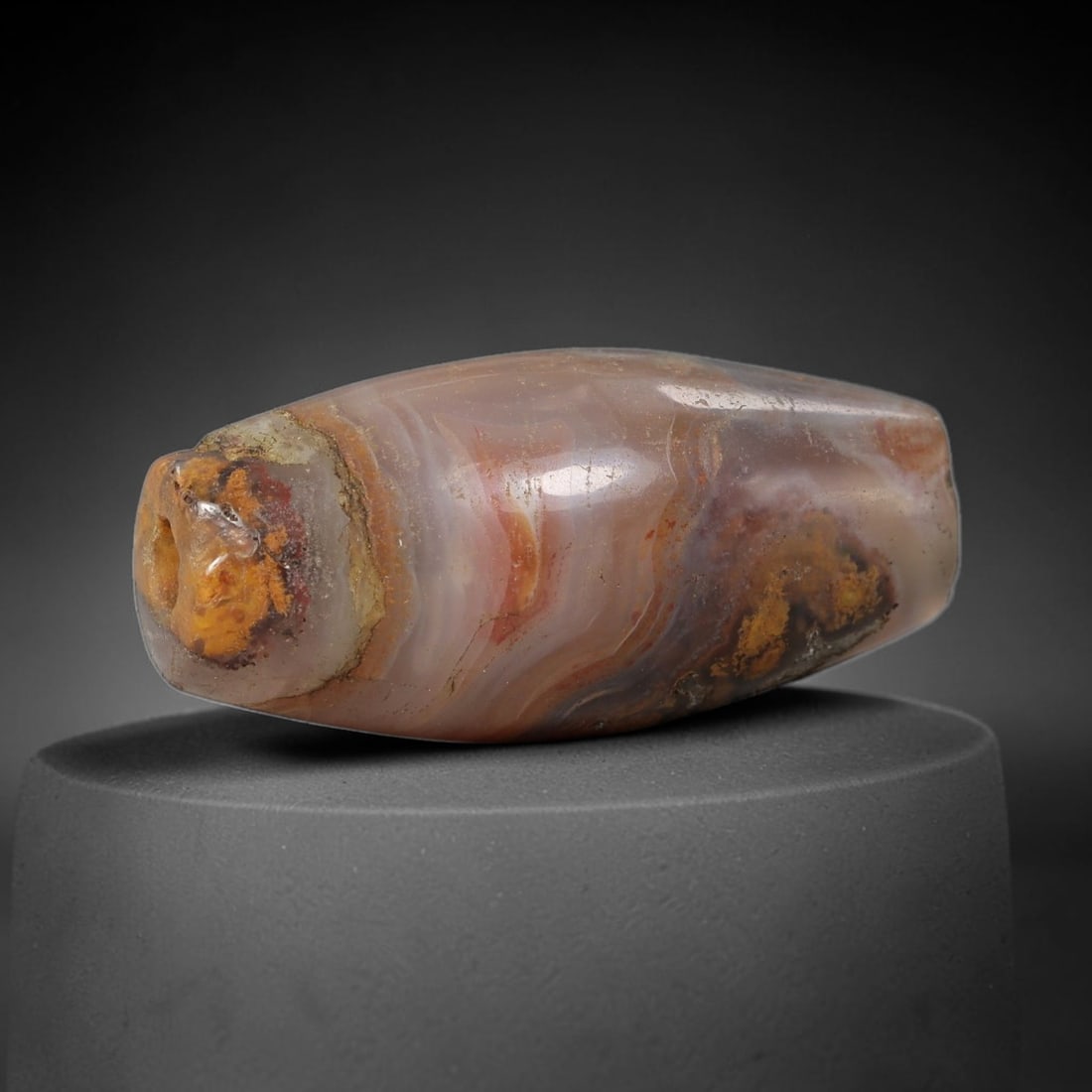 Ancient Agate Bead - Silk Road Bicone Amulet: Carved from banded agate, the bead features a smooth symmetrical bicone (double-pointed) form with a polished surface that highlights the stone's striking multi-layered banding, including warm amber,