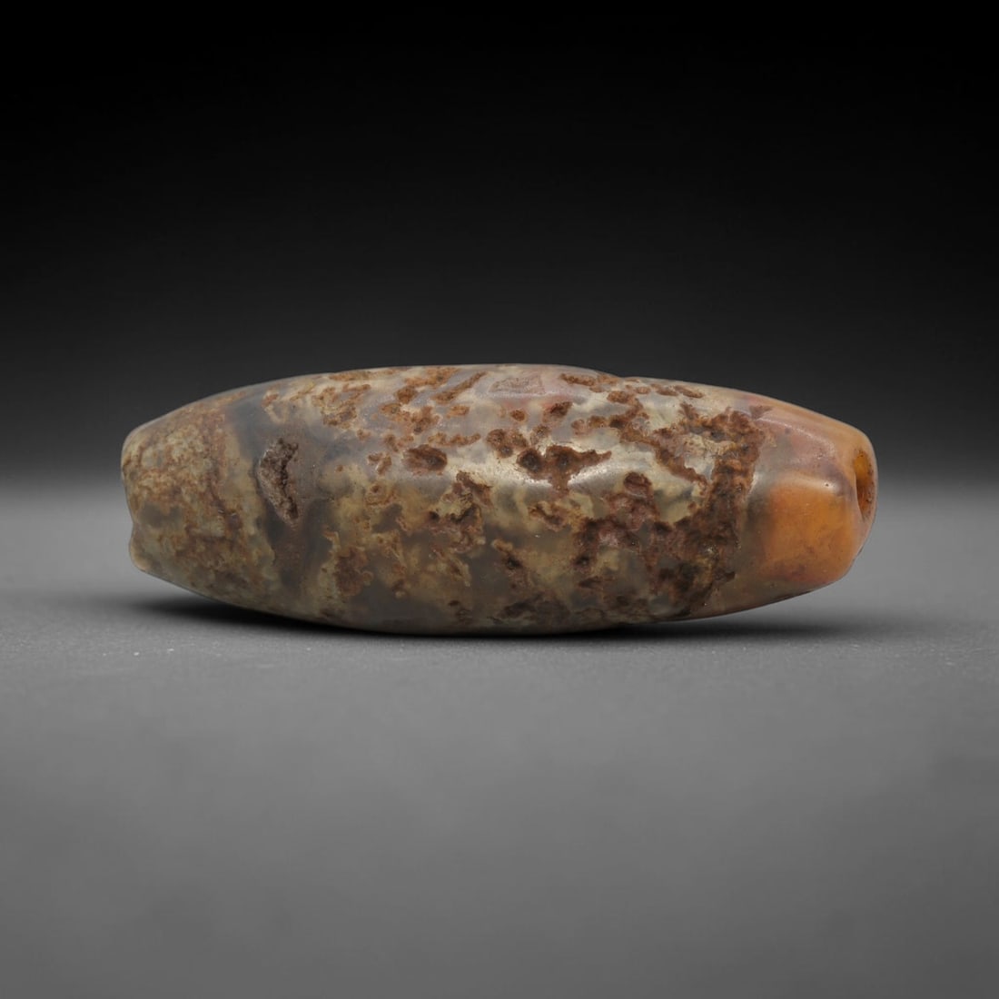 Ancient Jasper Bead - Silk Road Western Asiatic: This artifact is crafted from natural jasper, displaying a complex blend of earthy brown, amber, and cream mineral hues with prominent dendritic and vuggy inclusions across its textured surface. The b