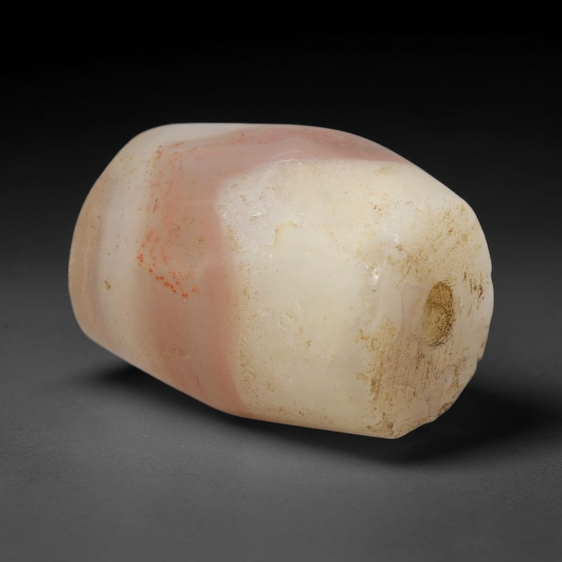 Ancient Pink Agate Bead - Western Asiatic Miniature Amulet: This bead is expertly carved from naturally banded translucent pink agate, showcasing fine lapidary craftsmanship consistent with the ancient bead-making traditions of the Indus Valley and Bactrian re