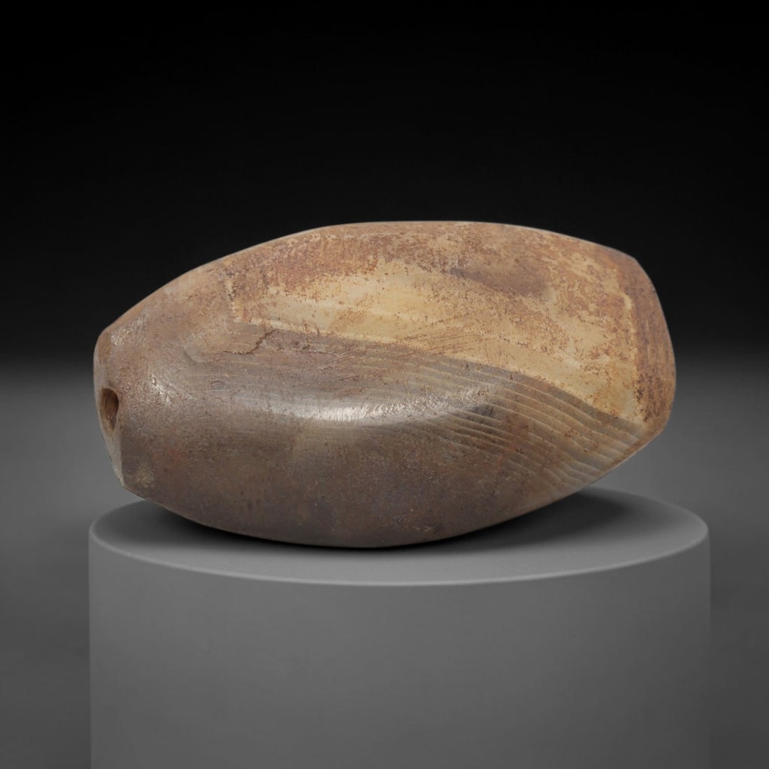 Ancient Agate Bead - Silk Road Bactrian Carving: This artifact is crafted from banded agate, showcasing robust, parallel banding in creamy beige and deep greyish-brown tones, with a heavily textured, earthy patina across its surface. The bead is sha