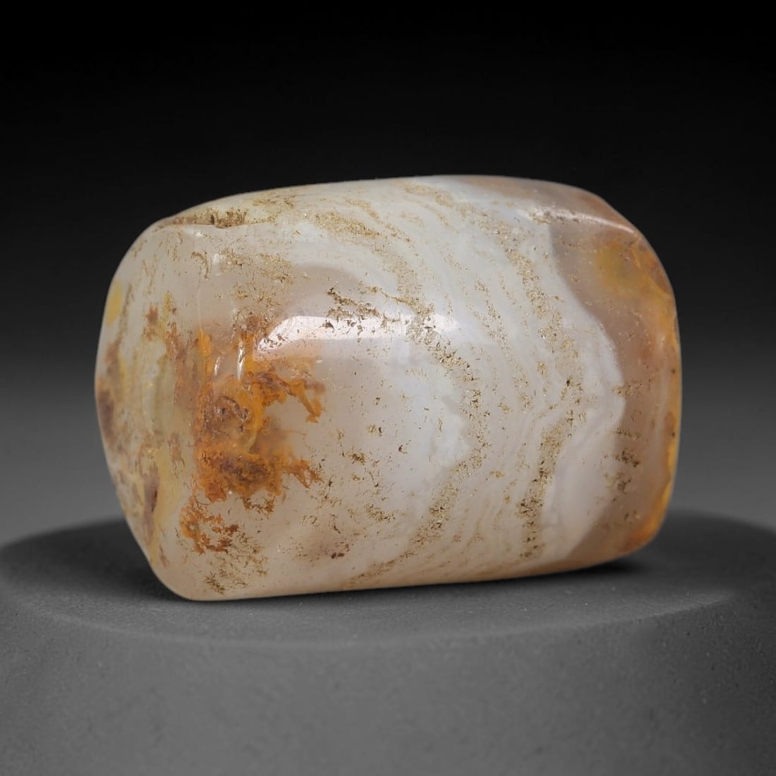 Ancient Banded Agate Bead - Indus Valley Artifact: This artifact is crafted from natural banded agate, shaped into a short, cylindrical barrel form with striking wavy white and amber banding. The bead features a central perforation for suspension, con