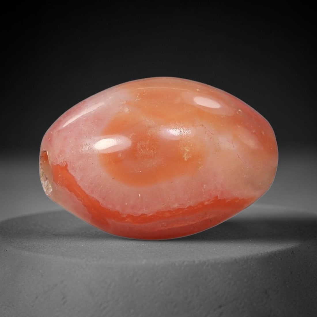 Ancient Carnelian "Eye" Agate Bead - Silk Road Indus Valley Barrel Bead: Carved from carnelian agate, the bead is fashioned in a compact barrel form, centered with a drilled perforation for easy suspension. The stone features a dramatic, eye-like banding pattern in vibrant