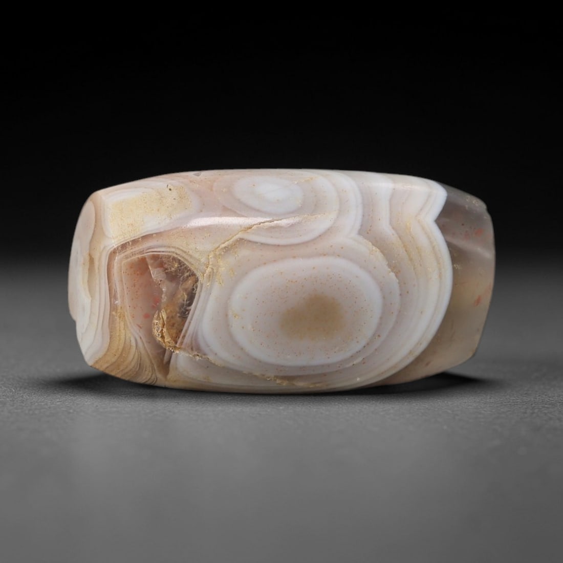 Ancient "Eye" Banded Agate Bead - Silk Road Indus Valley Barrel Bead: Carved from banded agate, the bead is fashioned in a compact barrel form, with a central drilled perforation for suspension. The stone exhibits a spectacular natural "eye" pattern, featuring concentri