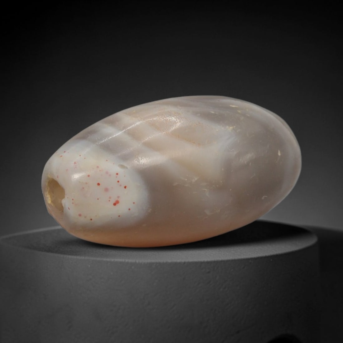 Ancient Agate Bead - Silk Road Bactrian Amulet: This bead is carved from naturally banded translucent agate, exhibiting expert lapidary craftsmanship characteristic of ancient Bactrian and Silk Road bead-making traditions. The ovoid barrel form fea
