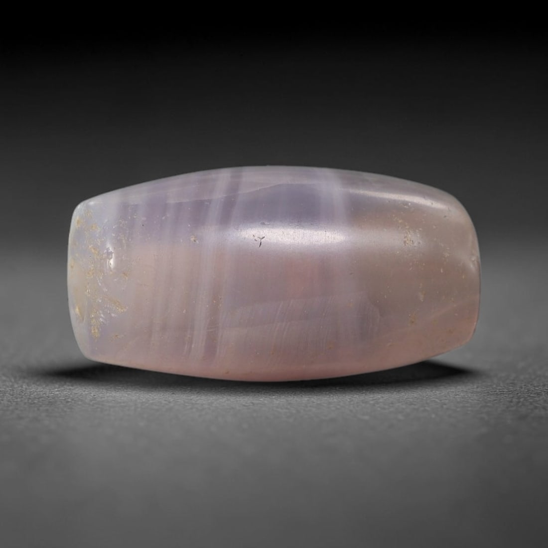 Ancient Lavender Banded Agate Bead - Indus Valley Artifact: This artifact is crafted from natural lavender banded agate, shaped into a compact barrel form with delicate parallel banding in soft lilac and pale pink hues. The bead features a central perforation
