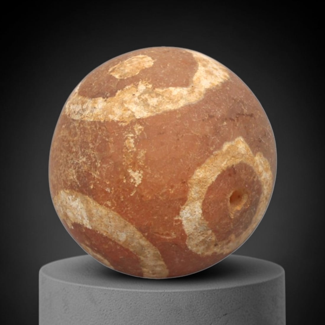 Ancient Carnelian Etched Bead - Gandhara Spherical Bead, 60XY: The bead is crafted from carnelian, a semi-precious chalcedony, with a spherical form and laterally drilled suspension hole. Its surface features an etched white pattern of concentric circular and ban