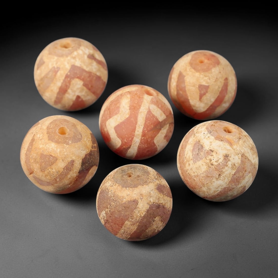 Ancient Carnelian Etched Beads - Gandhara Amulet Set, 36BE: Set of six spherical beads crafted from carnelian, each decorated with etched geometric motifs in a pale white pigment, characteristic of Gandharan decorative traditions. The beads retain a well-devel