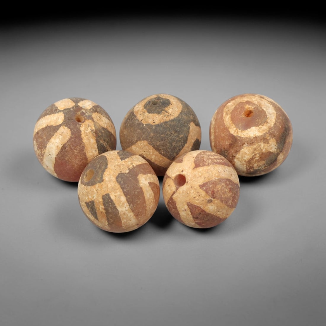 Ancient Carnelian Etched Beads - Gandhara Amulet Set, 74XY: Set of five spherical beads crafted from carnelian, each decorated with etched geometric motifs in a pale white pigment, characteristic of Gandharan decorative traditions. The beads retain a well-deve