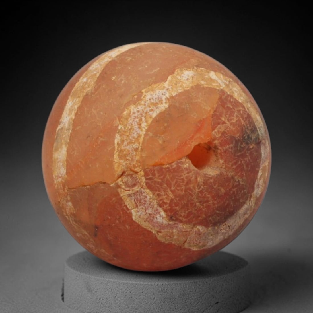 Ancient Carnelian Etched Bead - Gandhara Spherical Bead, 14XY: The bead is fashioned from carnelian, a semi-precious chalcedony, with a spherical form and a laterally drilled suspension hole for wear. Its surface is decorated with an etched white pattern of conce