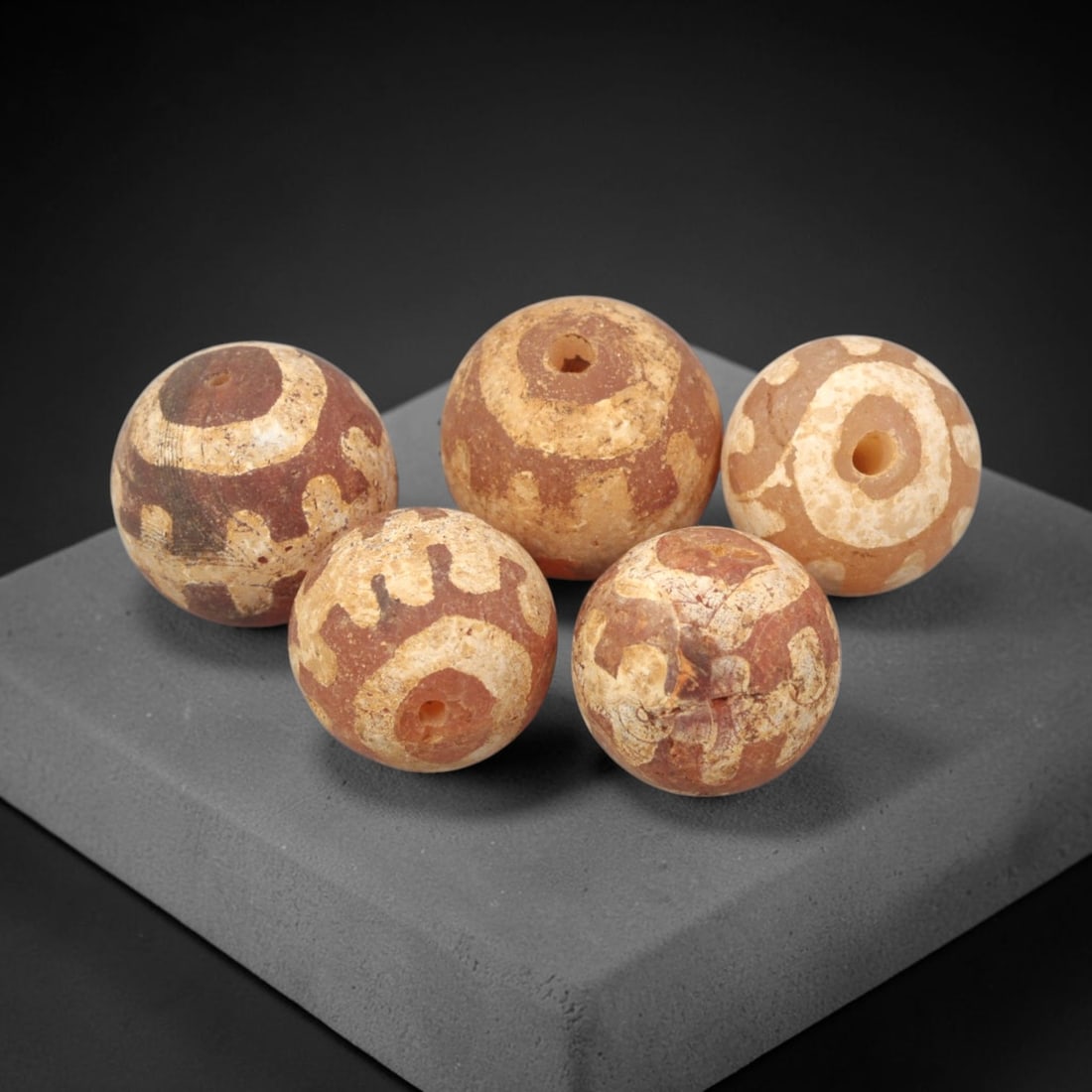 Ancient Carnelian Etched Beads - Gandhara Amulet Set, 78XY: Set of five spherical beads crafted from carnelian, each decorated with etched circular and geometric motifs in a pale white pigment, characteristic of Gandharan decorative traditions. The beads retai