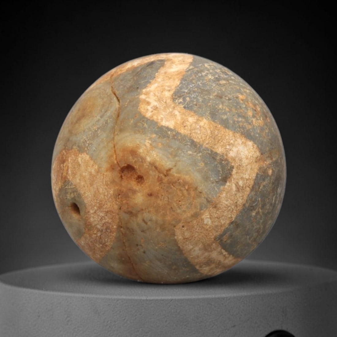 Ancient Carnelian Etched Bead - Gandhara Spherical Bead, 28XY: The bead is carved from carnelian, a semi-precious chalcedony, with a spherical form and a laterally drilled suspension hole. Its surface is decorated with an etched white zigzag geometric pattern, cr